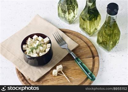 White cheese on a wooden board with olive oil on a white background.. Marinated feta on a wooden board with olive oil on a white background