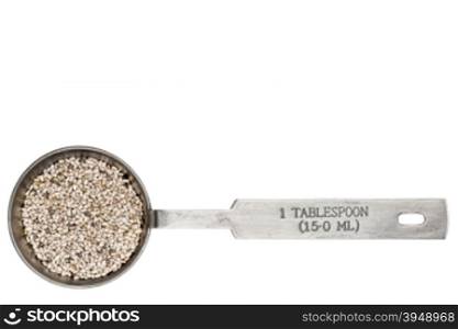 white chia seeds in a metal measuring tablespoon isolated on white