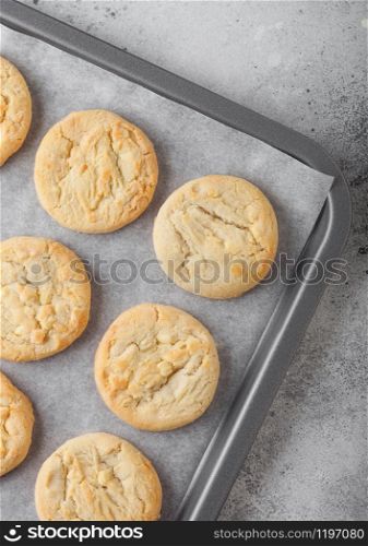 White chocolate biscuit cookies on baking tray on light table background.