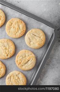 White chocolate biscuit cookies on baking tray on light table background.