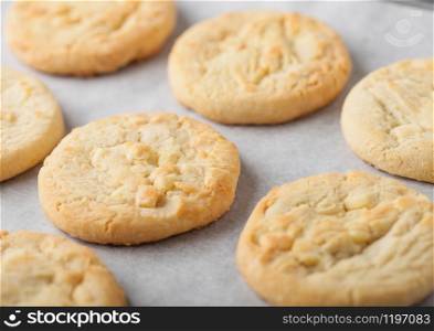 White chocolate biscuit cookies on baking tray on light table background. Macro