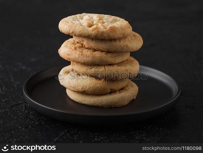 White chocolate biscuit cookies on black ceramic plate on black table background.