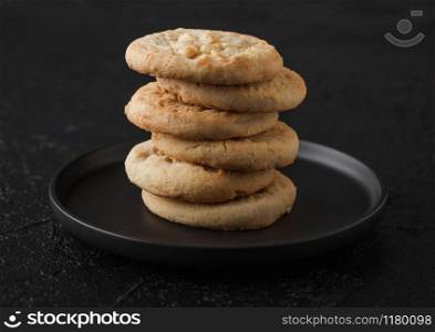White chocolate biscuit cookies on black ceramic plate on black table background.