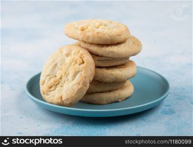 White chocolate biscuit cookies on blue ceramic plate on blue table background.