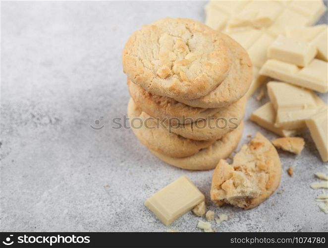 White chocolate biscuit cookies with chocolate blocks and curls on light table background. Space for text