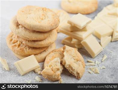 White chocolate biscuit cookies with chocolate blocks and curls on light table background.