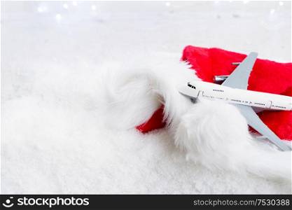 White christmas background with snow and lights. Christmas red hat and plane. Holiday travel and vacations concept.. White christmas with snow