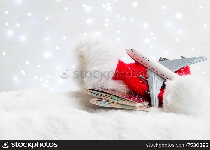 White christmas background with snow and lights. Christmas red hat, plane and passports. Holiday travel and vacations concept.. White christmas with snow
