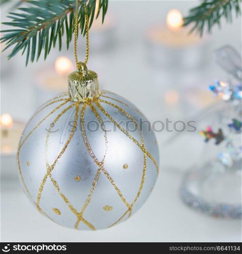 white christmas ball hanging on fir tree and candle lights defocused background