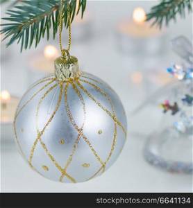 white christmas ball hanging on fir tree and candle lights defocused background