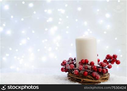 White christmas - burning candle in snow, blue night with lights in background. Happy Christas and holidays concept.. White christmas with snow