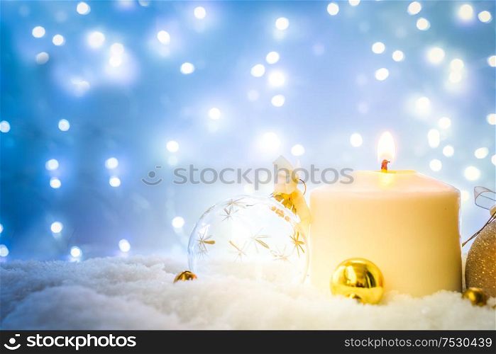 White christmas - burning candle in snow, blue night with lights in background, retro toned. White christmas with snow