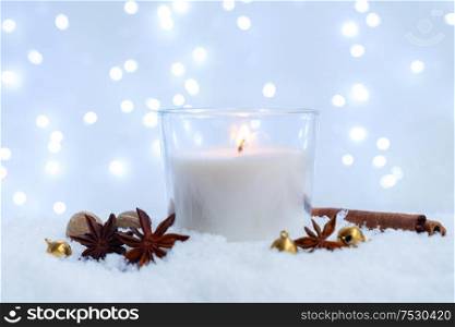 White christmas - glowing candle with spices in snow, blue night with lights in background. Happy Christas and holidays concept.. White christmas with snow