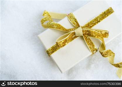 White christmas. - golden gift box with ribbon in snow. White christmas with snow