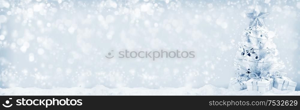 White christmas tree with silver decorations and gifts on snow on bokeh background. Christmas tree and gifts