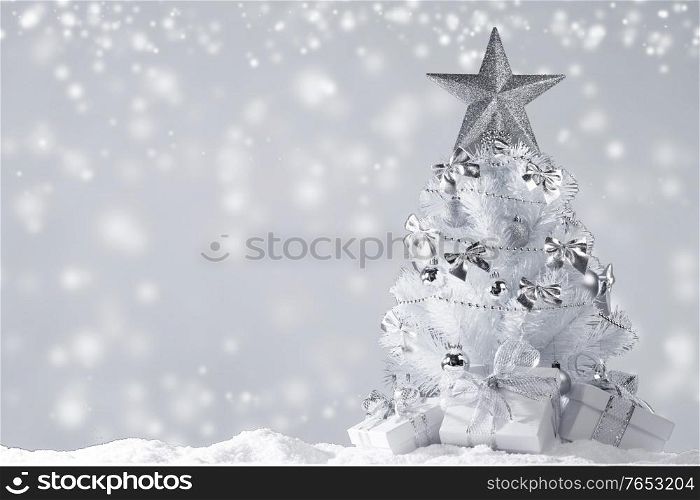 White christmas tree with silver decorations and gifts on snow on magic lights background. Christmas tree and gifts