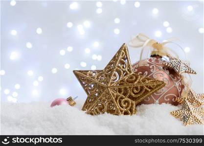 White christmas with snow - pink and golden balls and star close up with lights in background. White christmas with snow