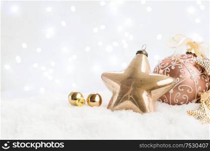 White christmas with snow - pink and golden balls and star close up with lights in background. Happy Christas and holidays concept.. White christmas with snow