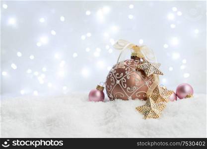White christmas with snow - pink and golden balls with lights in background. Happy Christas and holidays concept.. White christmas with snow