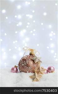 White christmas with snow - pink and golden decorations with lights in background. Happy Christas and holidays concept.. White christmas with snow