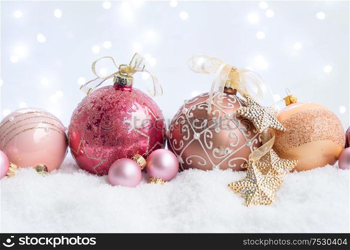 White christmas with snow - pink and golden decorative balls with lights in background. Happy Christas and holidays concept.. White christmas with snow