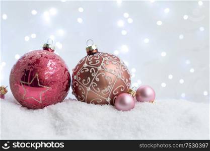 White christmas with snow - pink balls with lights in background. Happy Christas and holidays concept.. White christmas with snow