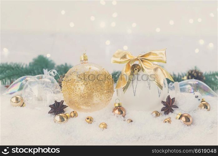 White christmas with snow styled scene - white and golden decorations and fir tree twig, bokeh lights in background, retro toned. White christmas with snow