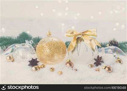 White christmas with snow styled scene - white and golden decorations and fir tree twig, bokeh lights in background, retro toned. White christmas with snow