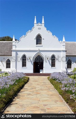 White Church in Franschhoek in front of blue sky with stone pathway