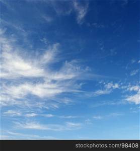 White cirrus clouds against the dark blue sky. background.
