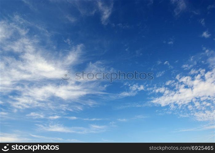 White cirrus clouds against the dark blue sky. Heavenly background.