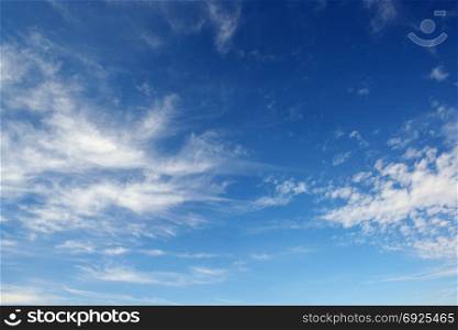 White cirrus clouds against the dark blue sky. Heavenly background.