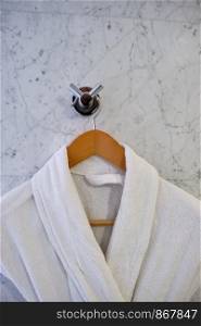 White Clean bathrobes hanging on wooden hanger. Two Clean bathrobes