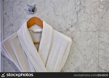 White Clean bathrobes hanging on wooden hanger. Two Clean bathrobes