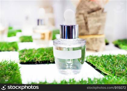 White clear glass bottle and pipette with a labels close up on green grass a light background