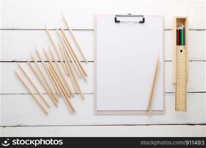 White clipboard with blank paper ,pencils, ruler and wood box on white wood background, template, mock up