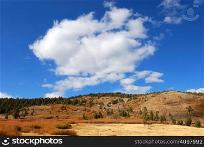 White cloud in blue sky above mountain side