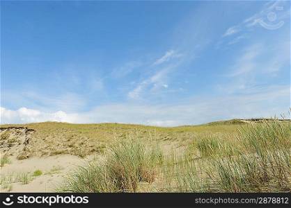 White clouds on blue sky over dunes