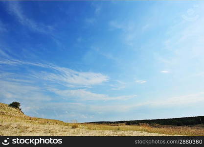 White clouds on blue sky over dunes