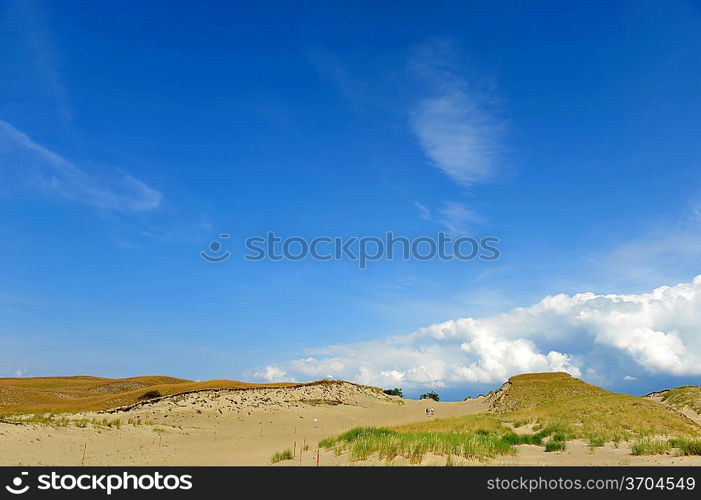 White clouds on blue sky over dunes