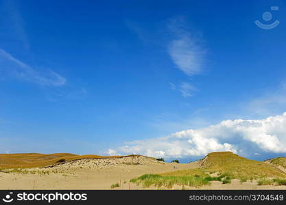 White clouds on blue sky over dunes