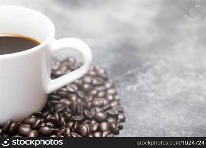White coffee cup and coffee beans dark on table Bare mortar cement style loft background. soft focus.