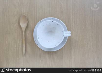White coffee cup and wooden spoon in top view on wood background for design concept food.