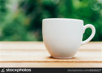 White Coffee Cup On Wooden Table In Green Garden
