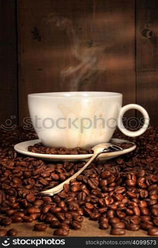 White coffee cup with spoon on roasted beans
