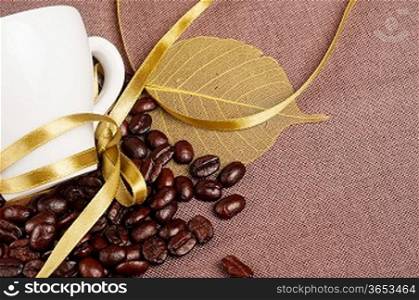 White coffee cup, yellow ribbon and coffee beans