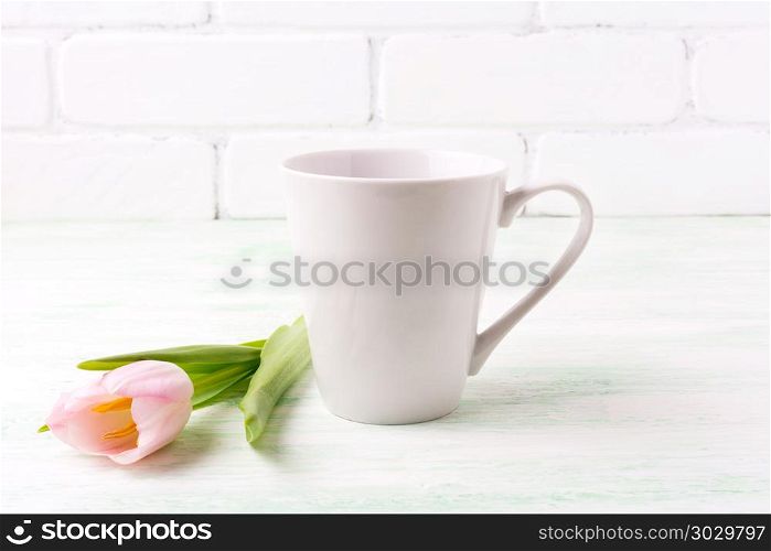 White coffee latte mug mockup with tender pink tulip flower. Empty mug mock up for design promotion. . White coffee latte mug mockup with pink tulip