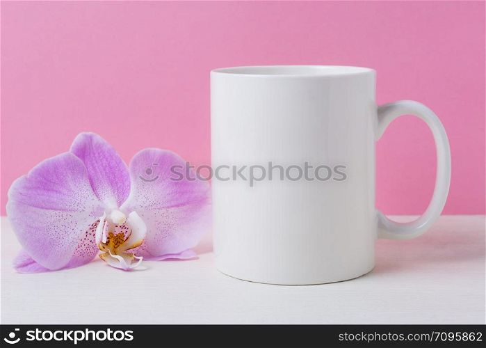 White coffee mug mockup on the pink background with purple orchid. Empty mug mock up for design promotion.