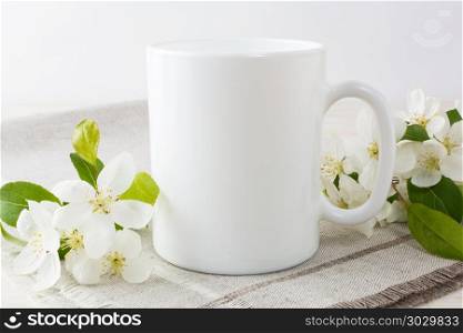 White coffee mug mockup with apple blossom. White coffee mug mockup with blossoming apple tree branch. Empty mug mock up for design promotion.
