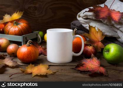 White coffee mug mockup with fall maple leaves, apples and pumpkins. Empty mug mock up for design promotion.